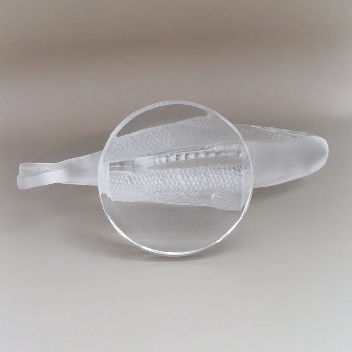 A frosted crystal fish sculpture, Perche Bouchon de Radiateur: Perch Car Mascot, displayed on a clear glass stand against a neutral beige background, base.