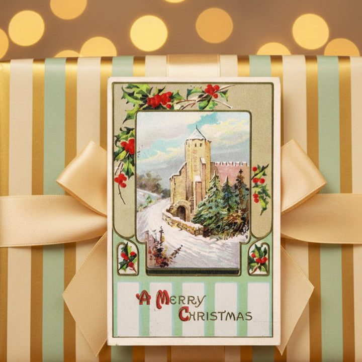 1916 Medieval Castle in Winter Antique Vintage Christmas Postcard placed on a wrapped gift with striped paper and a bow.