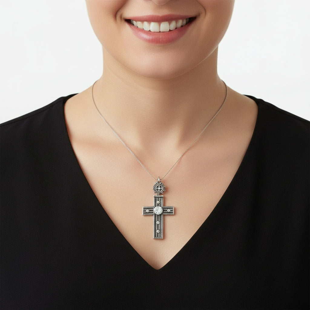 Woman wearing a necklace with a Vintage 1980s Mayan-Inspired Oxidized Cross Pendant with Cubic Zirconia Stone on a plain background.