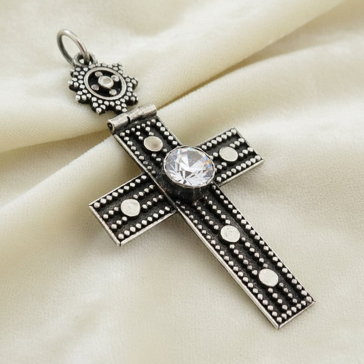 Vintage 1980s Mayan-Inspired Oxidized Cross Pendant with Cubic Zirconia Stone on plain background., side view.