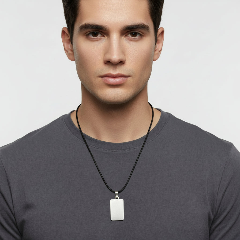 Man wearing a gray shirt with a black necklace featuring a silver pendant on a light gray background