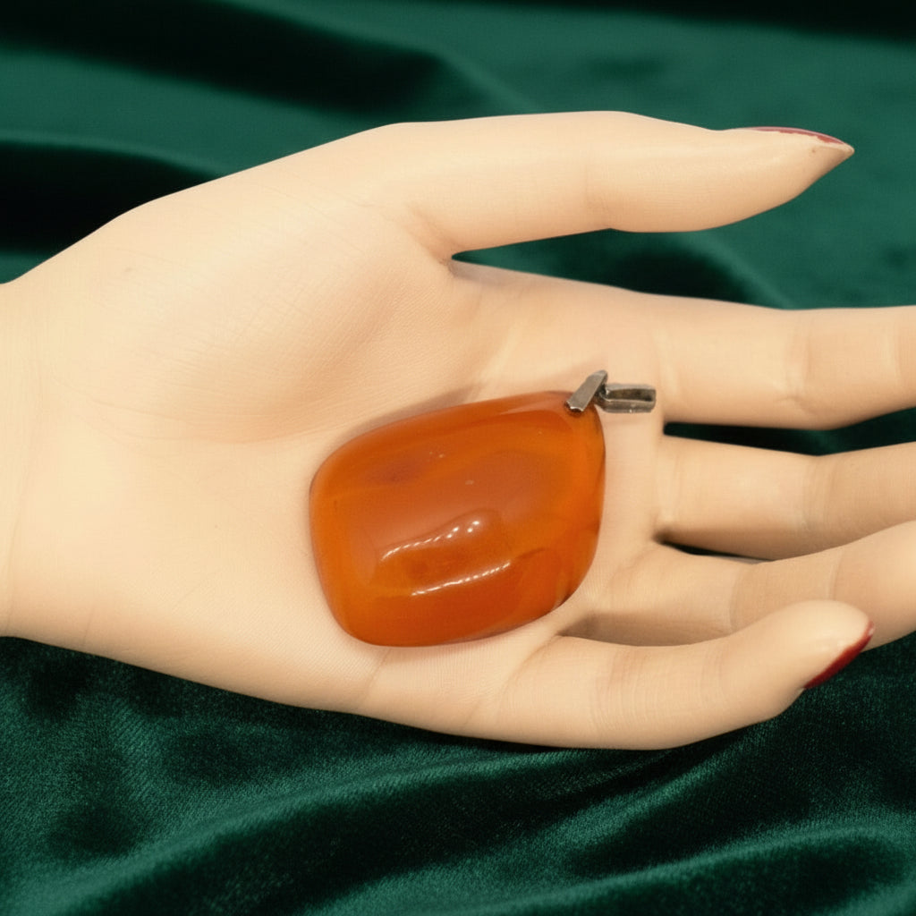 Large 1950s Vintage Soviet Baltic Amber Pendant in hand, green velvet background.