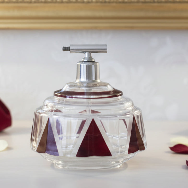 1930s Art Deco Palda Red Perfume Atomizer on a surface with rose petals, against a decorative mirror.
