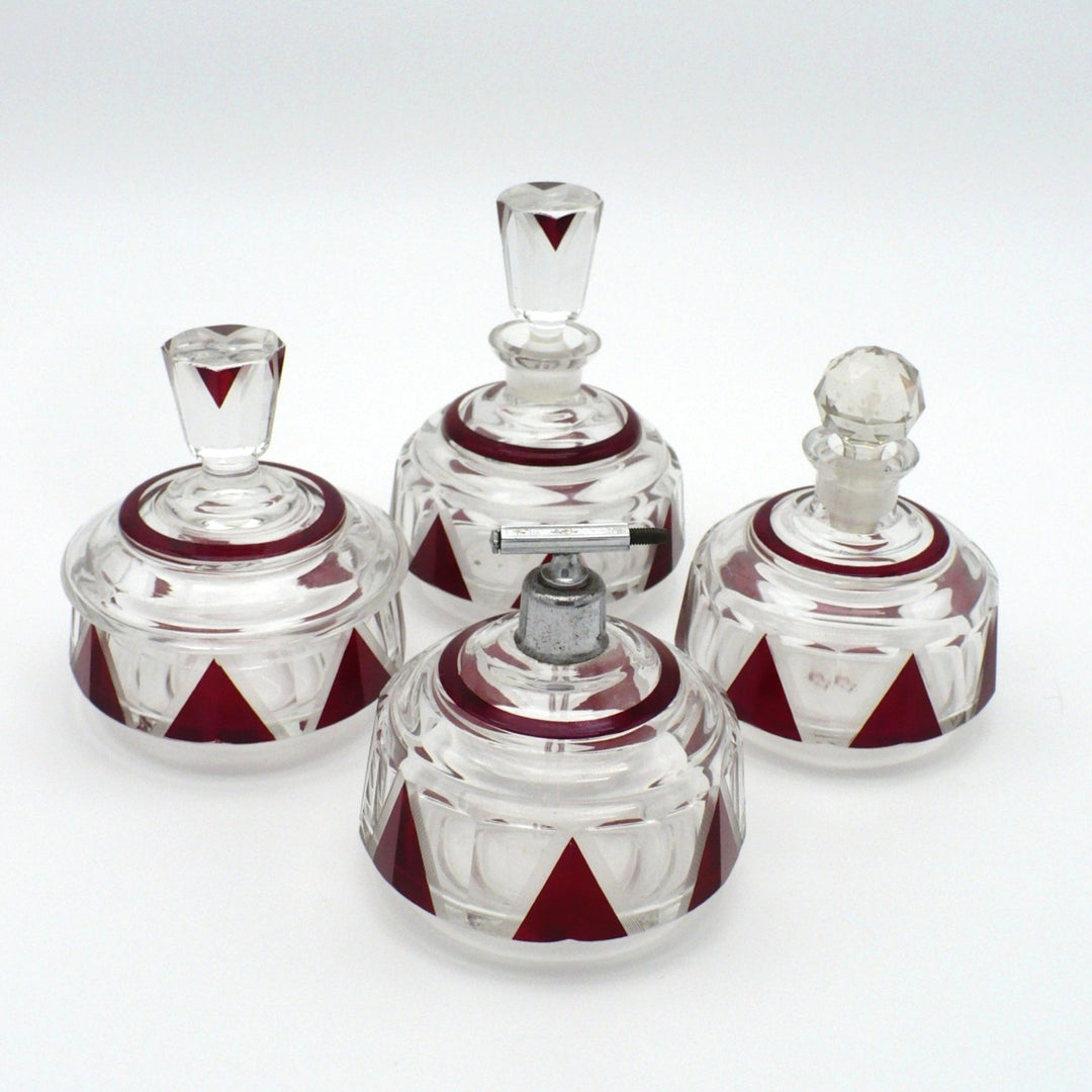1930s Karl Palda Art Deco crystal vanity set with red and clear geometric enameled glass against a white background.