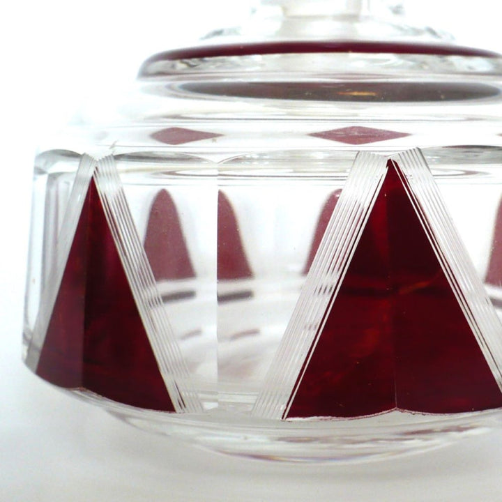 Close-up of a Karl Palda clear glass powder jar with a matching lid, decorated with faceted deep red enamel.