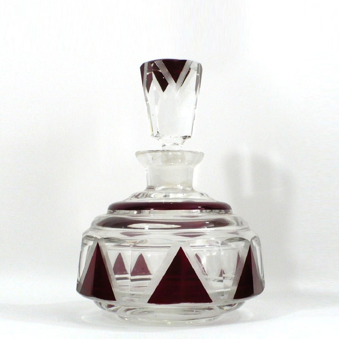 Karl Palda clear cut-glass decanter with a matching stopper, decorated with geometric dark red triangular patterns on the base and neck.