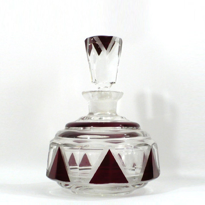 Karl Palda clear cut-glass decanter with a matching stopper, decorated with geometric dark red triangular patterns on the base and neck.