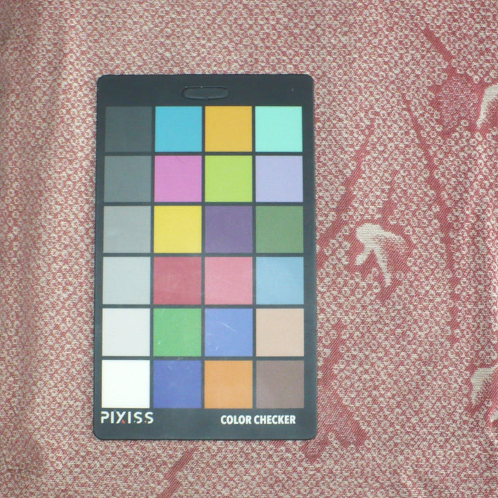 A Pixiss Color Checker card with a 6x4 grid of color squares, placed on kimono fabric background.