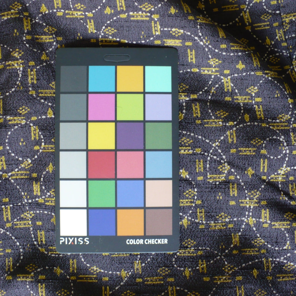 A Pixiss Color Checker card with a 6x4 grid of color squares, placed on kimono fabric background.
