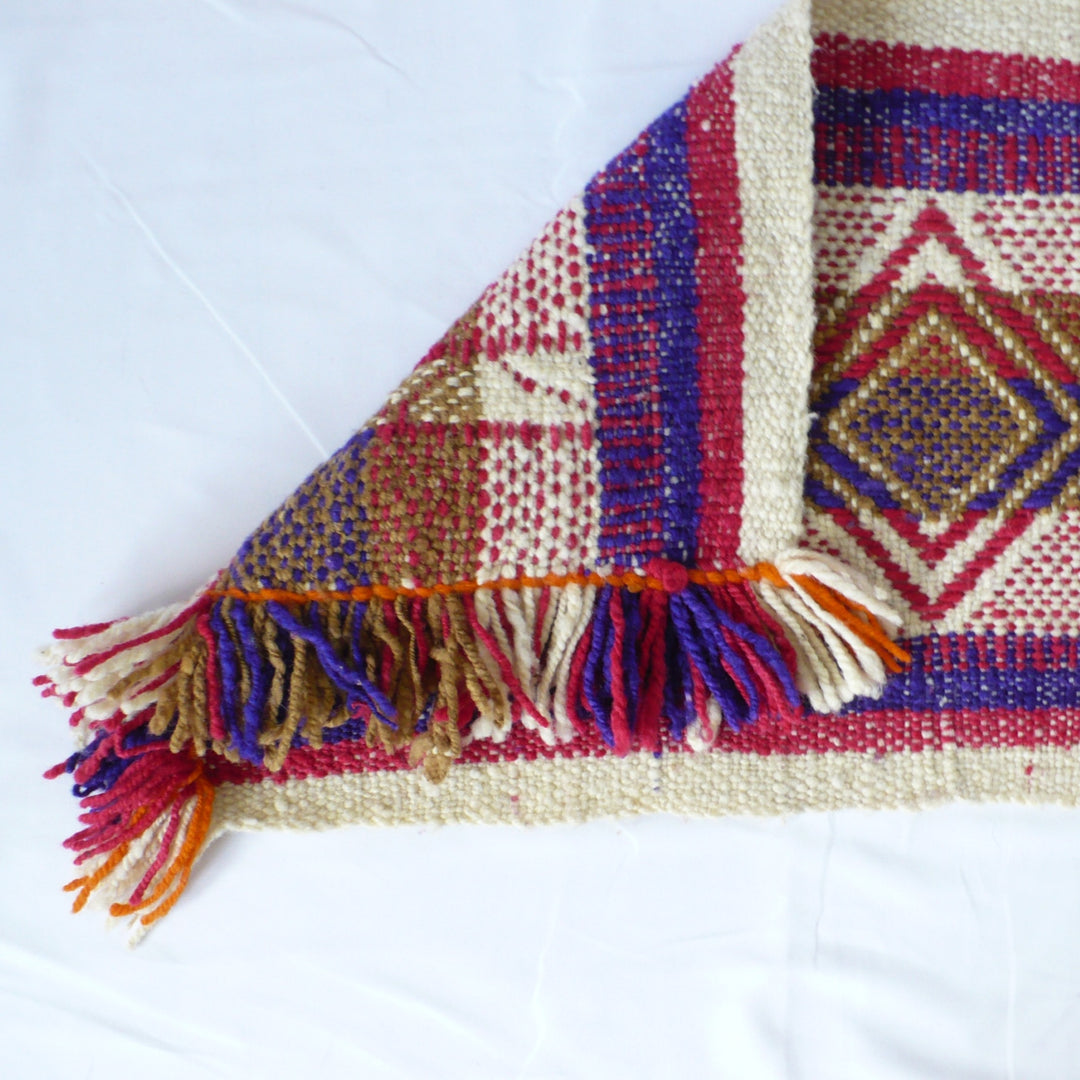 A close-up of a1960s Handwoven Table Runner (38-inches) - Argentina showing old over end displaying front and back, and fringe.