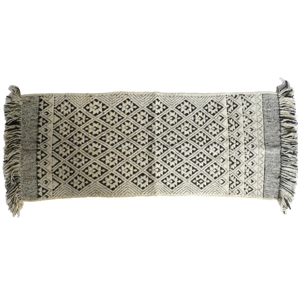 A rectangular woven runner rug with fringe on both ends, featuring a geometric diamond pattern in black and cream, 1950s Handwoven Mapuche Rug (55-inches) - Argentina.