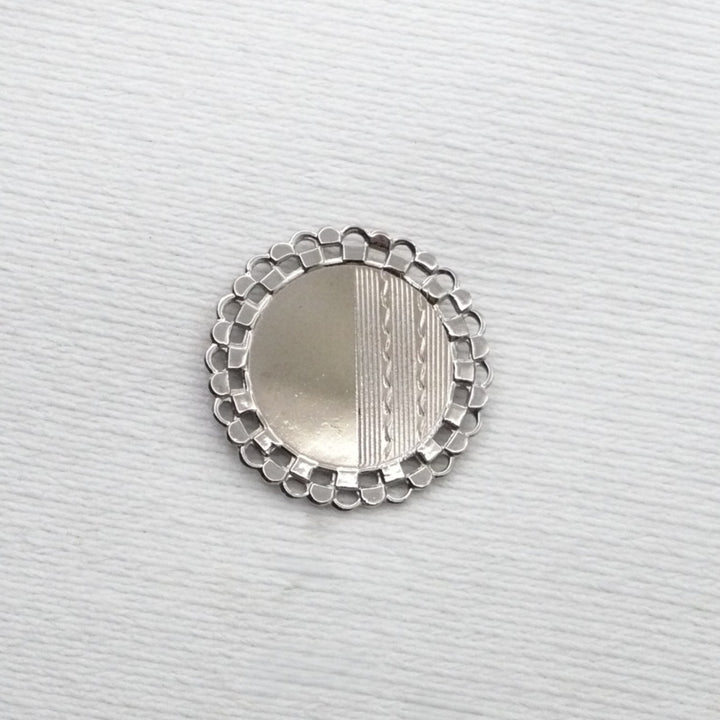 Silver decorative object on a textured white background