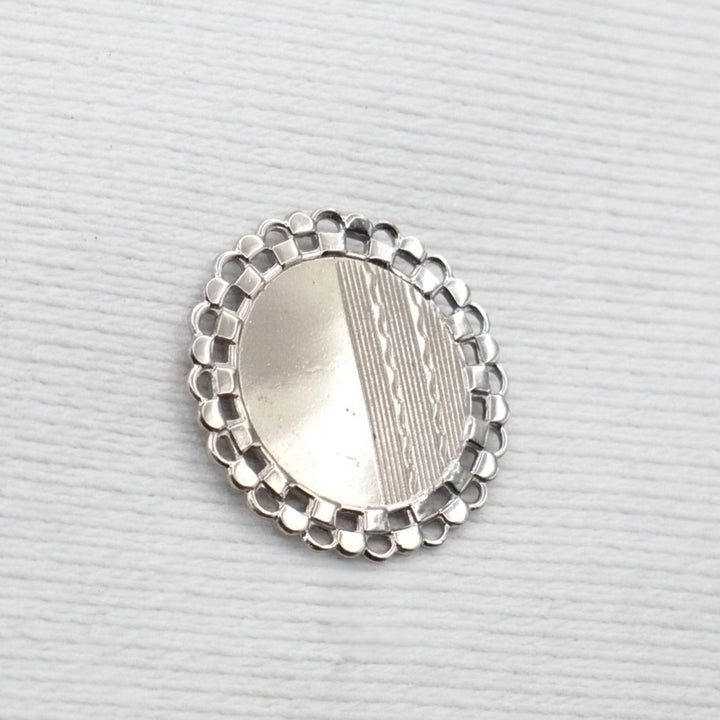 Silver decorative object with beaded edge on a light gray background