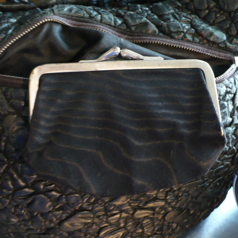 A close-up of a the black moire rayon fabric pouch with a silver metal kiss-lock  coin purse frame.