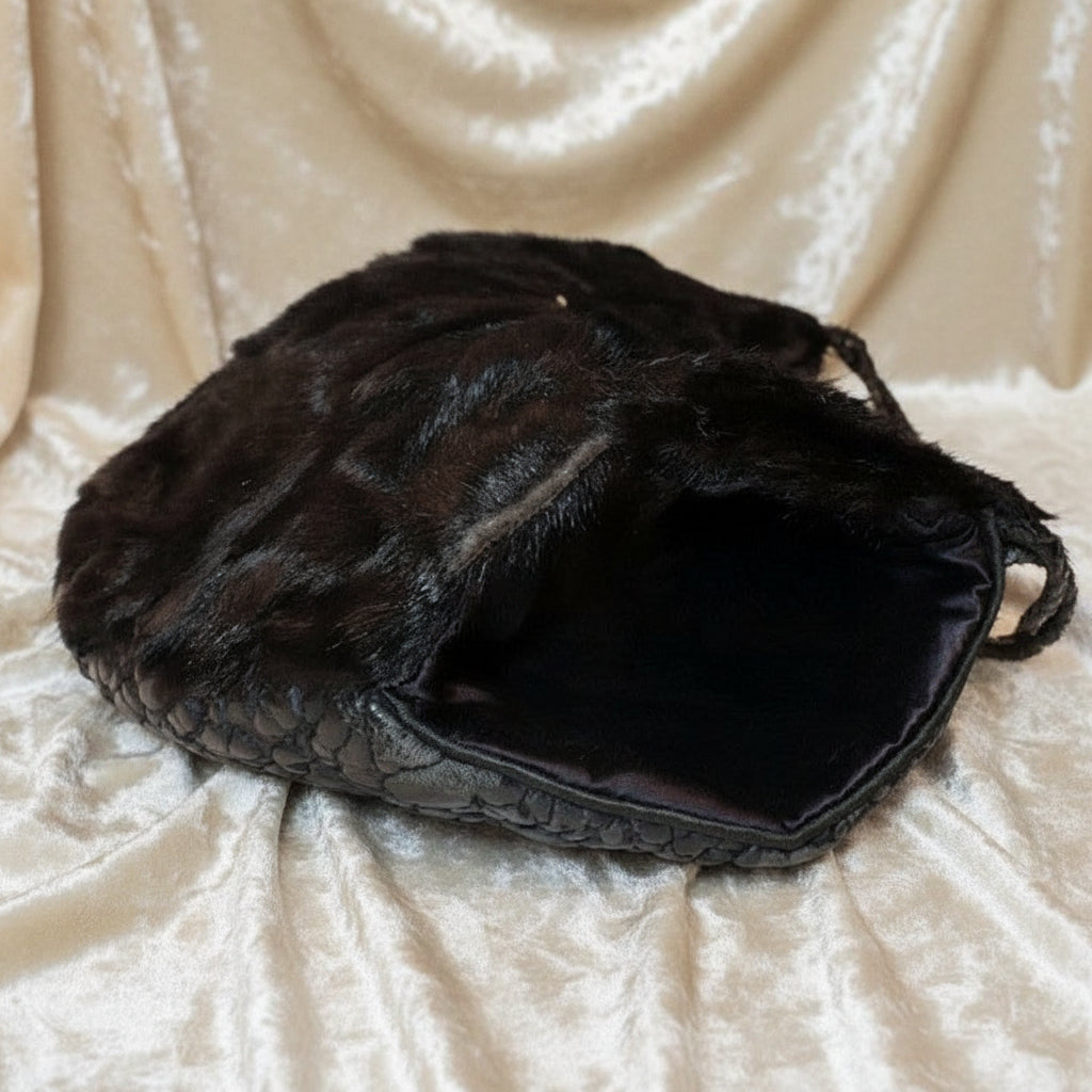 Interior view of the 1960s black broadtail lamb muff handbag showing the smooth black satin lining.