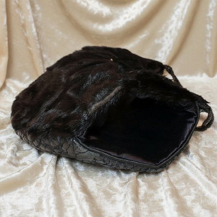 Interior view of the 1960s black broadtail lamb muff handbag showing the smooth black satin lining.