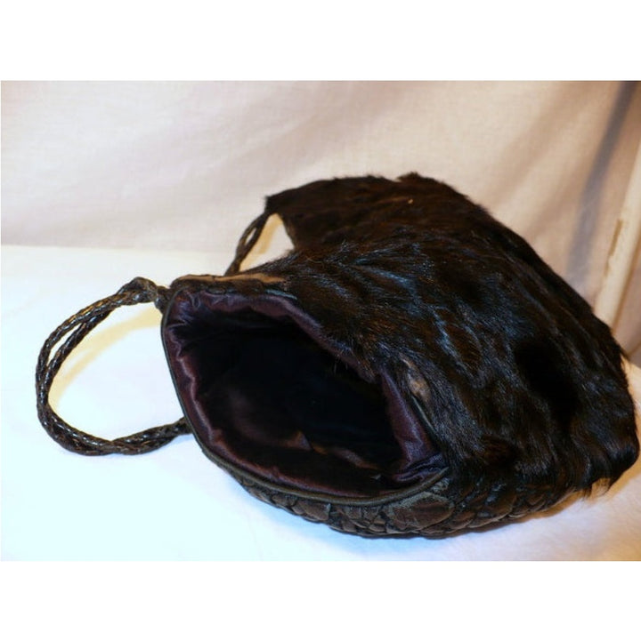 Interior view of the 1960s black broadtail lamb muff handbag showing the smooth black satin lining, opening of the right side.