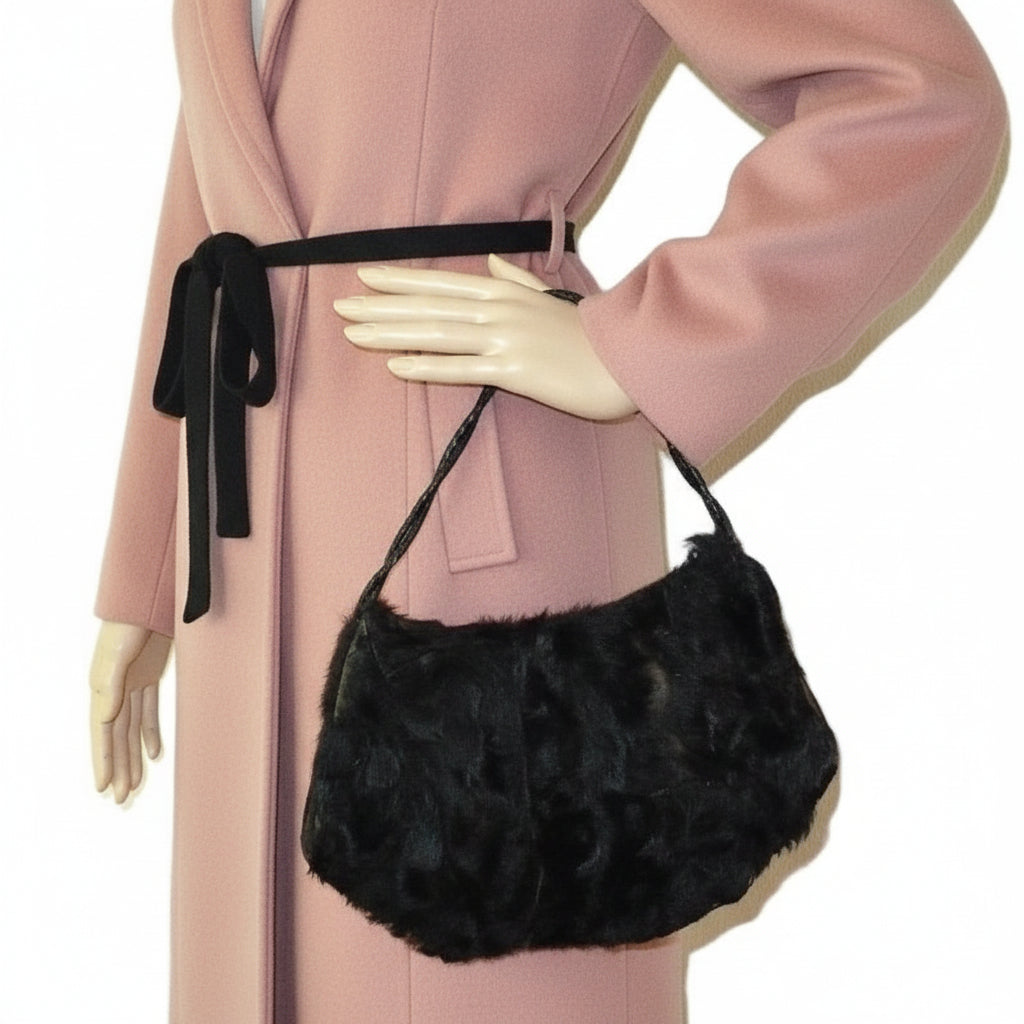 1930s Vintage Black Fur Carriage Muff with Hidden Coin Purse bag held by a person wearing a pink coat on a white background