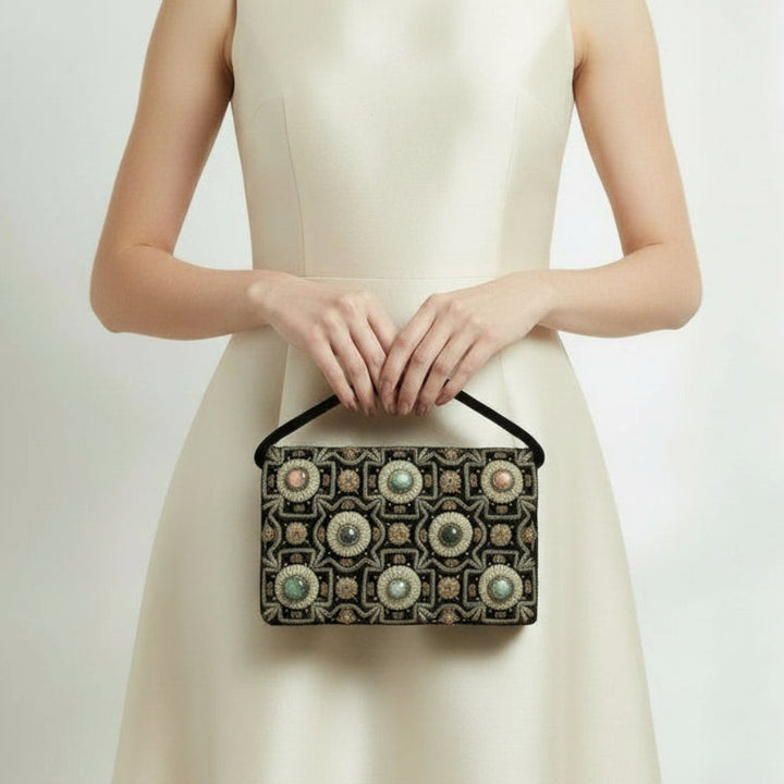 Woman holding a 1940s Vintage Black Velvet Anglo-Indian Genuine Gemstone Handbag, against a plain background