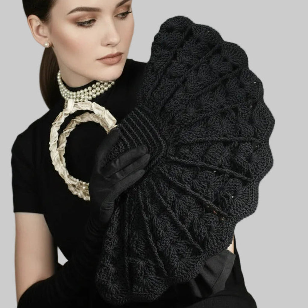 Woman holding a black 1940s Soutache Fan Handbag and black gloves against a gray background