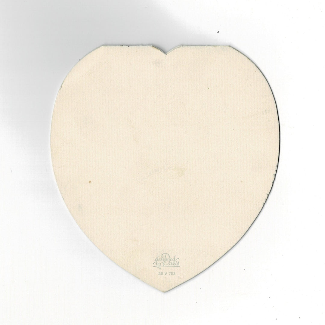 This elegant heart-shaped vintage Valentine’s Day card features a sophisticated construction where the sentiment is printed on a separate interior sleeve. The card follows a romantic Edwardian revival theme, with a real pink satin ribbon bow on the front that binds the interior sleeve to the die-cut outer shell. back side.