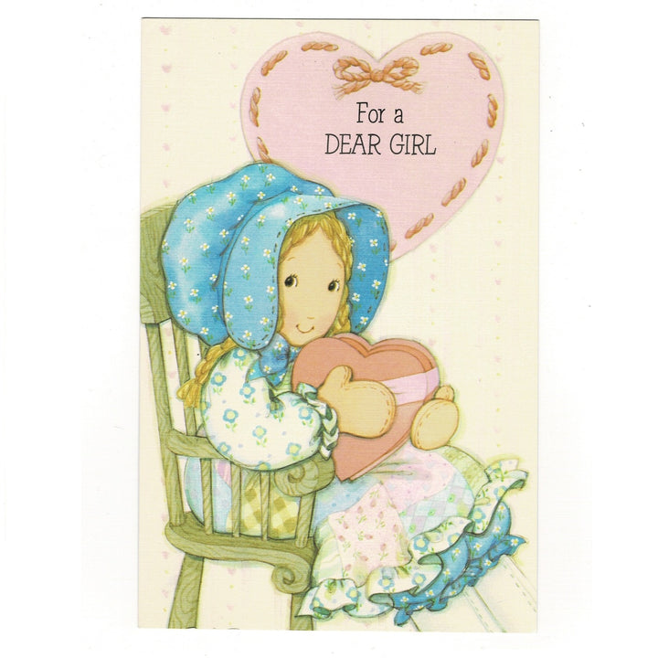 An illustrated vintage Valentine's Day card features a young girl in classic Holly Hobbie style, wearing a large blue-and-white floral sunbonnet and a patchwork dress. 