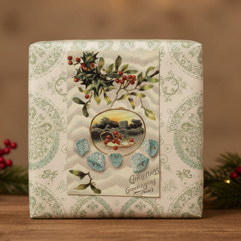 1909 Blue Christmas Bells and Winter Scene Vintage Postcard on a wooden surface.