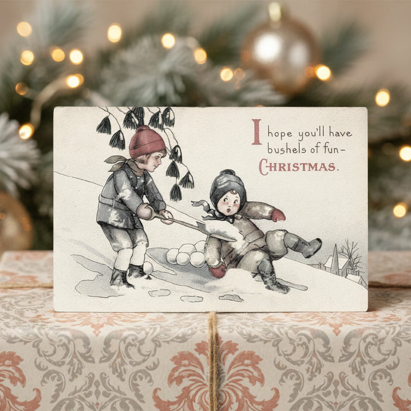 1921 Children Playing in Snow Christmas Vintage Postcard against a decorated Christmas tree background.