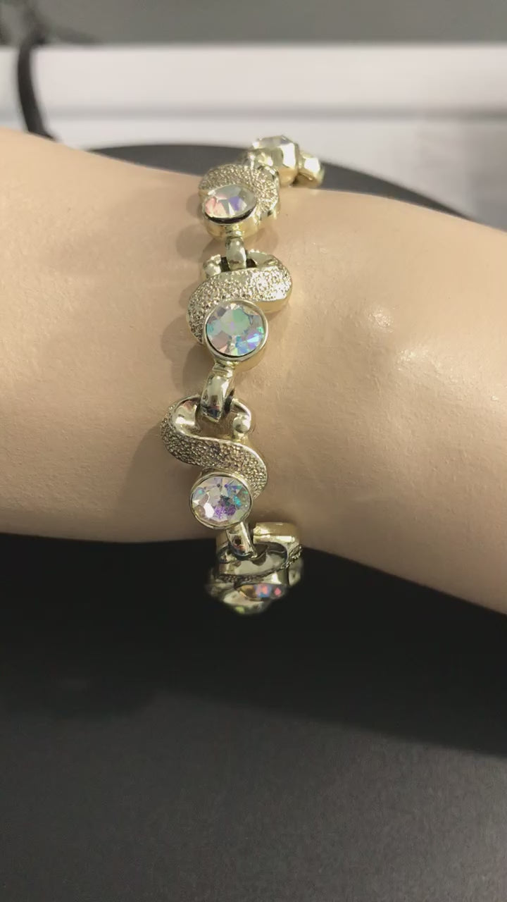 Video shows the aurora borealis crystal costume jewelry, vintage fashion jewelry bracelet. It is on a mannequin's wrist and turns in the light to show the vibrant rainbow colored crystals and textured links shining in the light. 