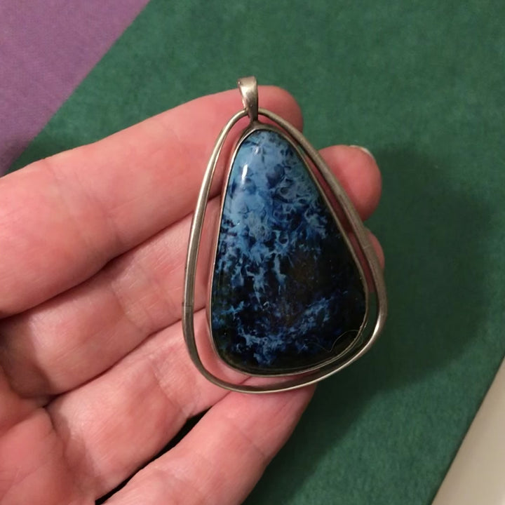 The teardrop cabochon is set in silver and hangs framed by teardrop silver frame. It moves inside the frame. 